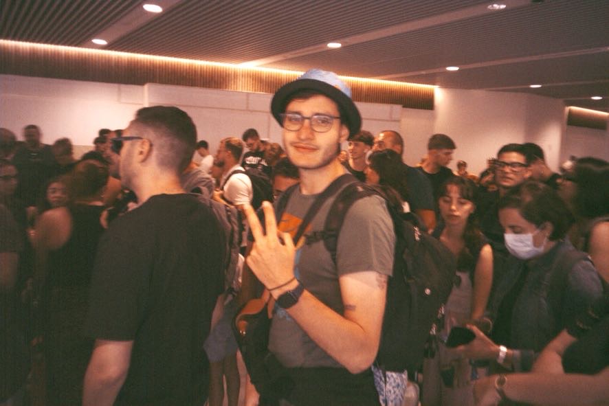 Marco, travel blogger di Ricordi di un Viaggio, pronto alla partenza in aeroporto con zaino e cappello da viaggiatore