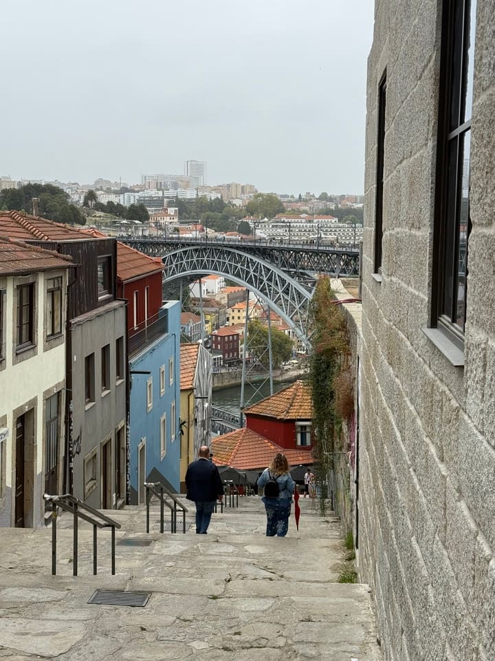 Discesa panoramica verso il Ponte Dom Luís I a Porto, con vista sulle tipiche case colorate e il fiume Douro sullo sfondo.