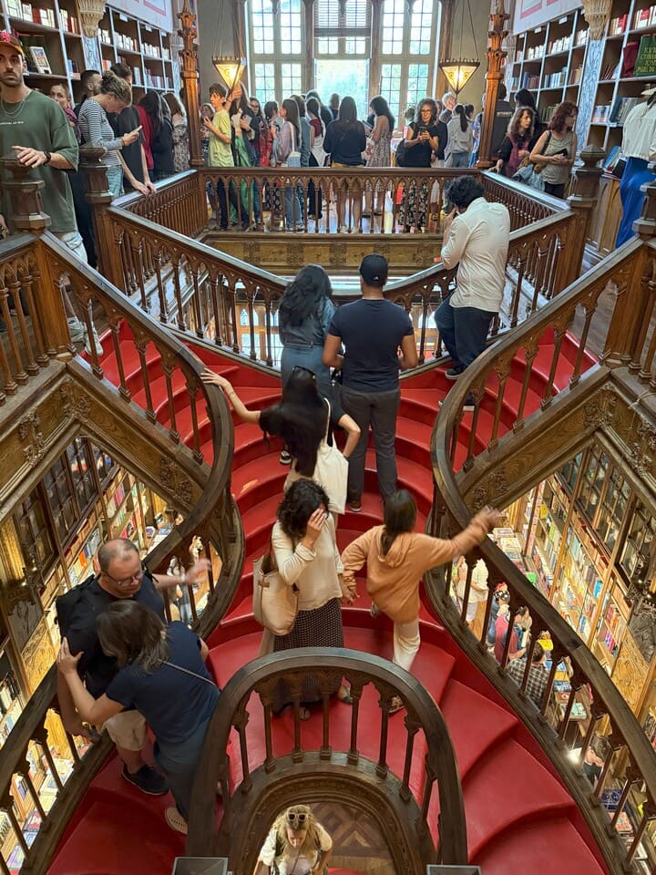Interno della Livraria Lello a Porto con la famosa scalinata rossa in legno, affollata di visitatori.