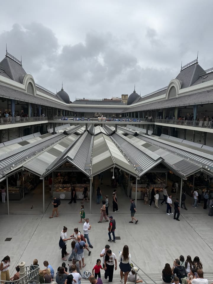 Vista panoramica interna del Mercado do Bolhão a Porto, con tettoie moderne e persone che passeggiano tra le bancarelle.