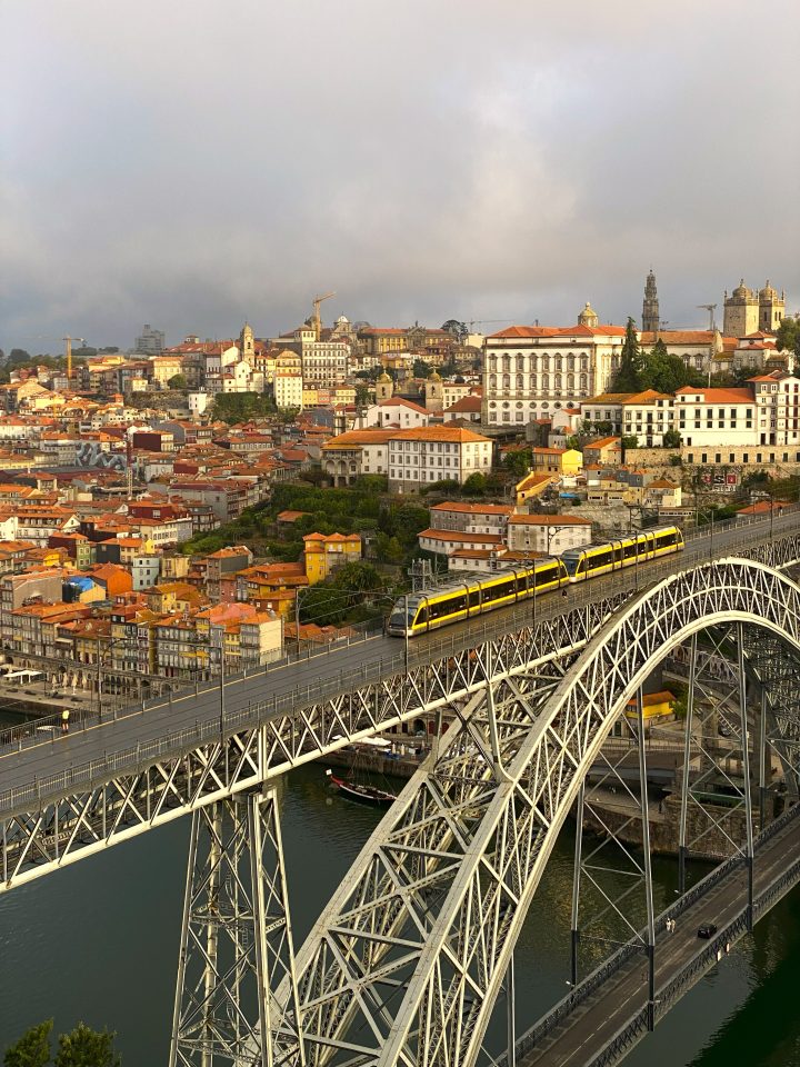 Vista panoramica di Porto con il Ponte Dom Luís I e il tram giallo che attraversa il fiume Douro all'alba