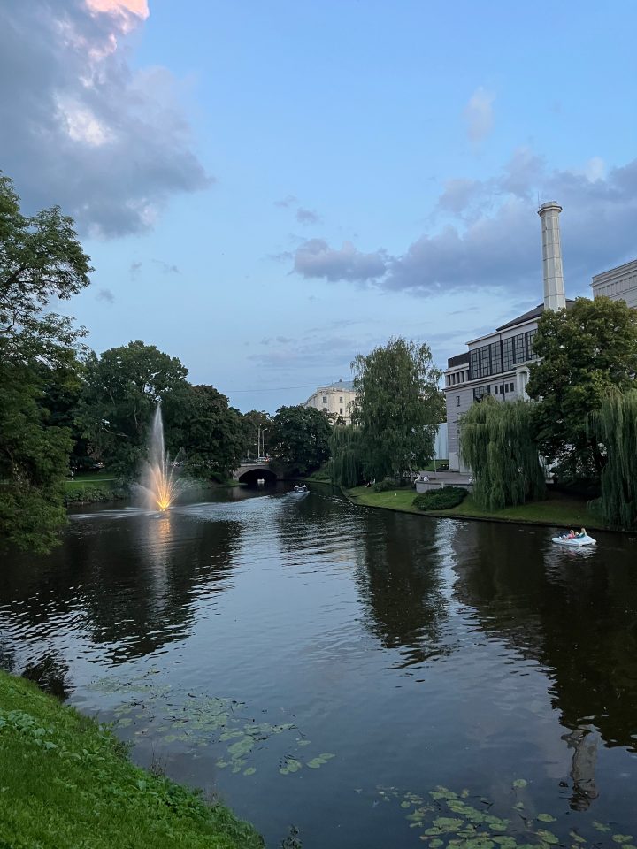 Parco Bastejkalns a Riga al tramonto con fontana illuminata e canale navigabile, uno dei luoghi più romantici e suggestivi della città.