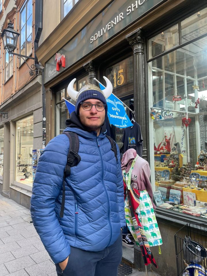 Turista con elmo da vichingo davanti a un negozio di souvenir a Gamla Stan, Stoccolma.
